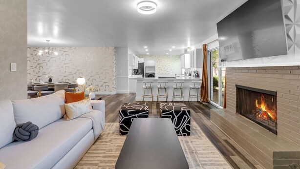 Een moderne woonkamer met een bank, poefjes, een salontafel en een open haard.