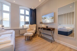 Une chambre à coucher avec un lit, une chaise, un bureau, un tableau et un miroir.