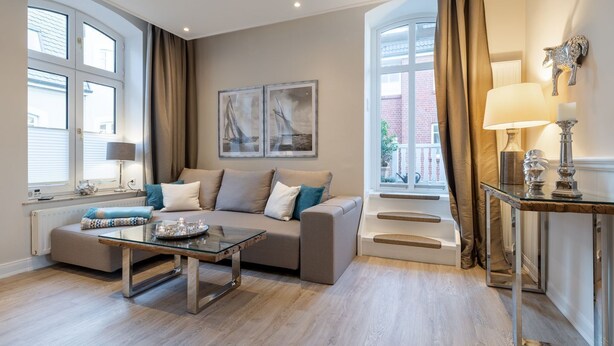 En moderne stue med en sofa, et glasbord og en trappe til en balkon.