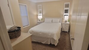 Une chambre à coucher avec un lit, des tables de chevet, une lampe et un miroir.