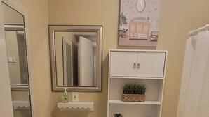 Une petite salle de bain comprenant un lavabo sur colonne, des toilettes et une petite étagère ornée d’objets décoratifs.