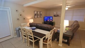 Un espace de vie compact comprenant un coin repas, un canapé, un téléviseur et une petite table avec une lampe.