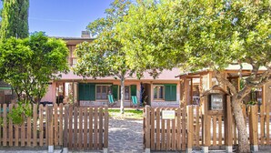 A gated entrance to a building with a stone pathway leading to a seating area with green chairs. - AZZURRO E CASA VERDE - CASA VERDE (Campo nell'Elba)