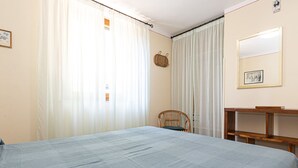A bedroom with a bed, a chair, a small table, and curtains. - AZZURRO E CASA VERDE - CASA VERDE (Campo nell'Elba)