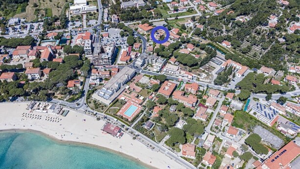 An aerial view of a coastal town with a beach, residential buildings, and a sports complex. - AZZURRO E CASA VERDE - CASA VERDE (Campo nell'Elba)