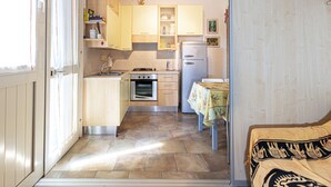 A compact kitchen with a stove, oven, and refrigerator. - Two-room apartment Lina, ground floor with fenced outdoor space near the center of Marina di Campo (Campo nell'Elba)