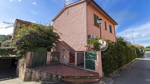 A two-story building with a brick facade, a satellite dish, and a small garden area with a fence. - Two-room apartment Lina, ground floor with fenced outdoor space near the center of Marina di Campo (Campo nell'Elba)