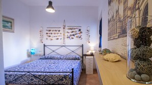 A bedroom with a bed, a nightstand, a wall-mounted lamp, and a decorative wall with various items.