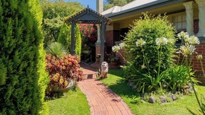 Un jardin avec un sentier, un kiosque et une maison en briques.