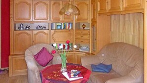 Ein Wohnzimmer mit einer Couch, einem kleinen Tisch mit einem Buch und einer Vase sowie Holzschränken mit Regalen.