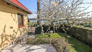Ein Haus mit rotem Dach und einem Garten mit blühendem Baum.