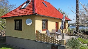 Ein kleines Haus mit rotem Dach, einem Balkon und Blick auf einen See.