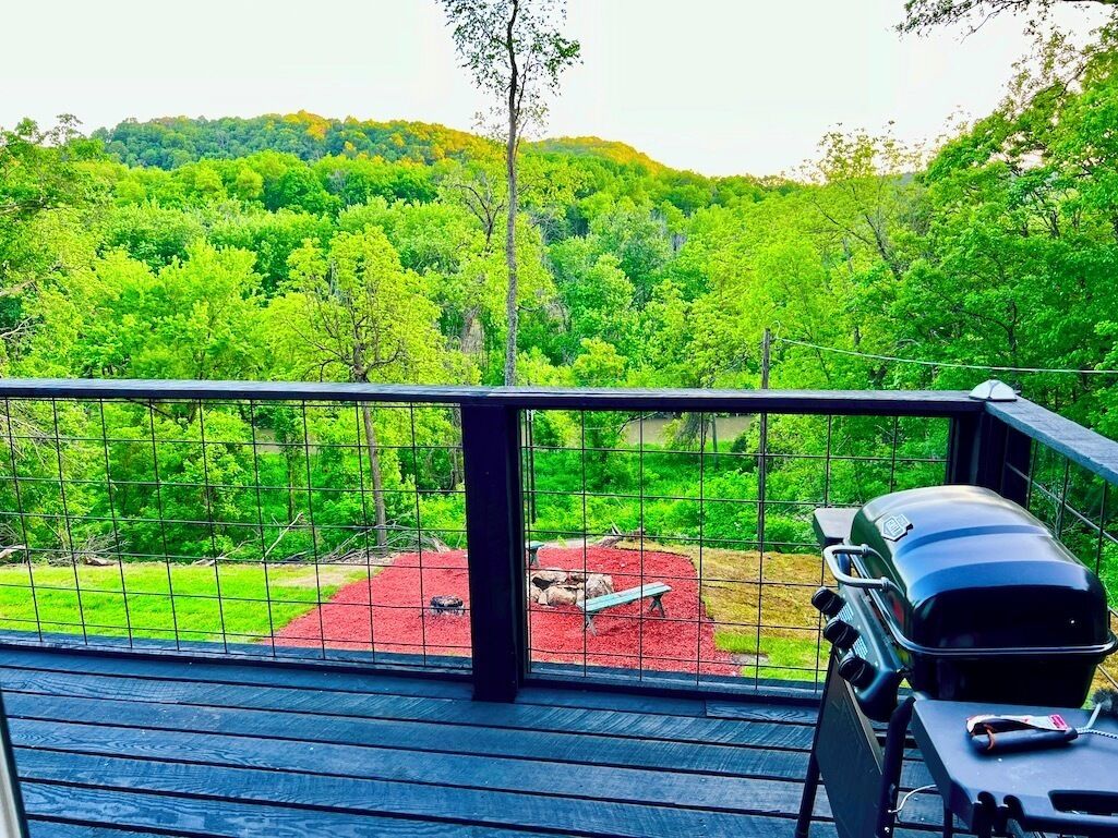 Un balcon avec un barbecue et une vue sur une zone boisée.