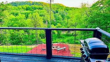 Un balcon avec un barbecue et une vue sur une zone boisée.