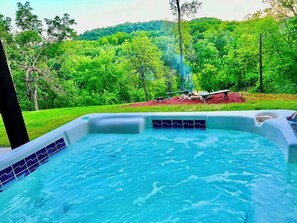 Un jacuzzi con vista a un área boscosa y un pozo de fuego.