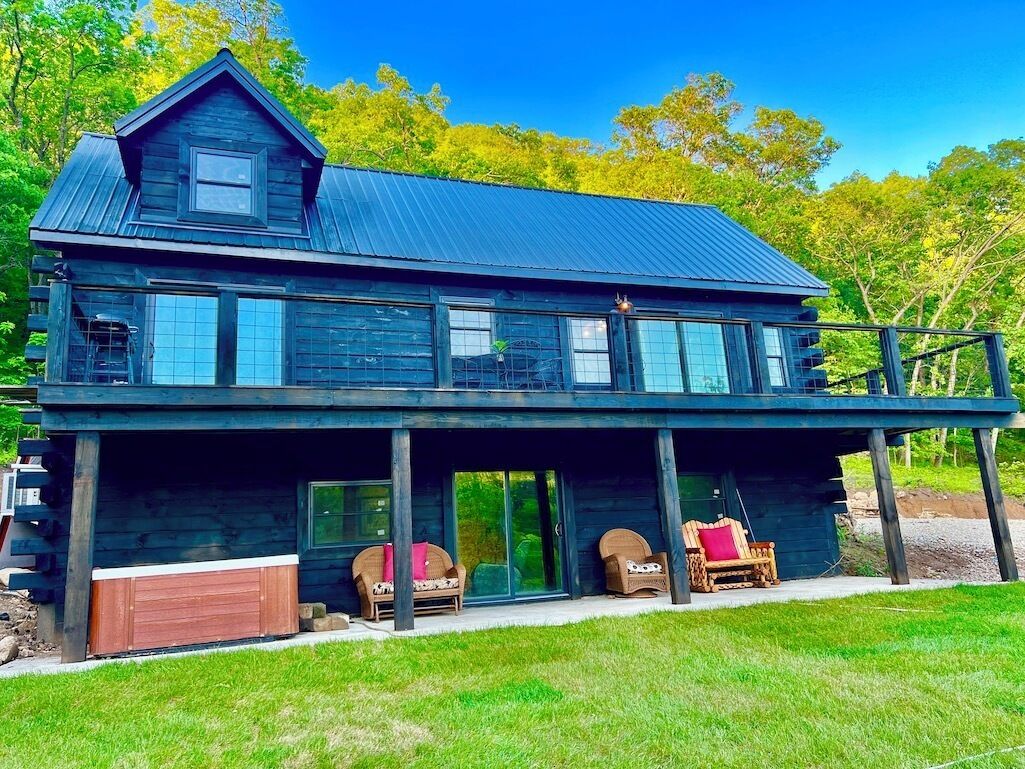 A two-story wooden house with a large porch, a garage, and a covered outdoor seating area.