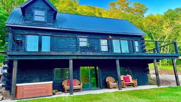 A two-story wooden house with a large porch, a garage, and a covered outdoor seating area.