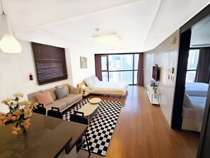 Relax in a spacious room with a large bed, sofa, and dining area, offering a city view.