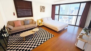 Una habitación de hotel moderna con un sofá, una cama, una mesita y una alfombra a cuadros.