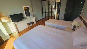 Une chambre d’hôtel avec deux lits, un bureau avec une télévision, une chaise et un grand miroir.