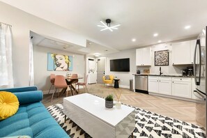 A modern living room with a blue sofa, a white coffee table, and a patterned rug. - ★ HostWise Stays ★ 3 Separate Apts in 1 Listing! Great for groups! Minutes to Stadium (Pittsburgh)