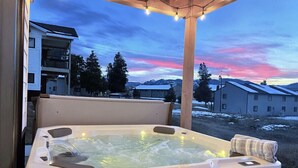 Una banyera d'hidromassatge amb vistes a un paisatge nevat i edificis al fons.