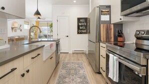 Una cuina moderna amb una illa central, electrodomèstics d'acer inoxidable i un penjall decoratiu.