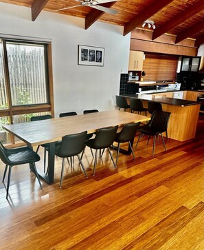 A modern kitchen with wooden cabinets, a central island, and a dining area with a wooden table and chairs.