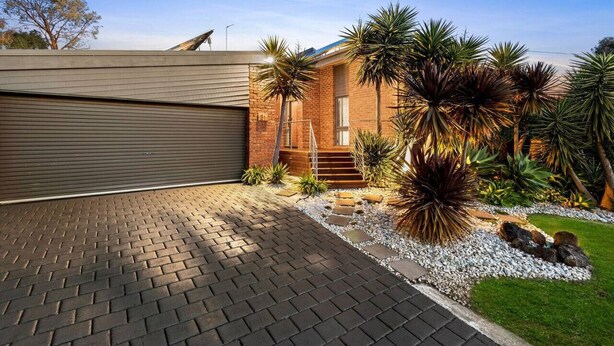 A modern house with a garage, a brick exterior, and a landscaped garden with various plants and a pathway. - The Weekender With Spa Sleeps 11 (Ocean Grove)