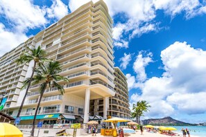 A multi-story hotel with balconies, a beachside location, and a view of the ocean.