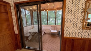 A room with a large sliding glass door leading to an outdoor deck with a wooden bench and a table. - The Half Shell, Oceanside Beach Cottage, 6 min walk to beach (Corolla)