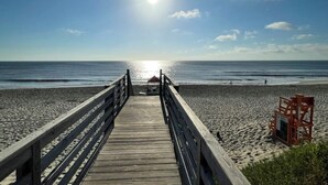 A wooden boardwalk leading to a beach with a lifeguard tower. - The Half Shell, Oceanside Beach Cottage, 6 min walk to beach (Corolla)