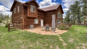 Une cabane en bois à deux étages, dotée d’un patio, d’un espace extérieur couvert avec des sièges et d’une cour clôturée.