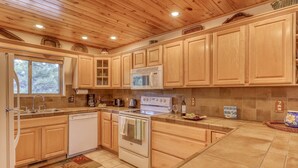 Une cuisine avec des meubles de rangement en bois, une cuisinière blanche, un four à micro-ondes et un lave-vaisselle.