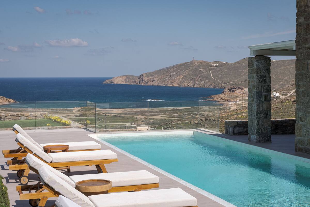 A poolside area with lounge chairs and a view of the sea.