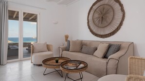 A modern living room with a beige sofa, two wicker side tables, and a large woven wall art piece. - Retreat Hill Luxury Villas Mykonos (Mykonos)