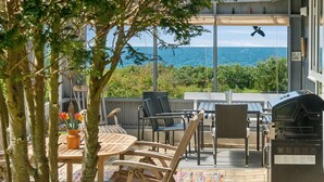 Une terrasse avec une table, des chaises et un barbecue.