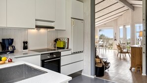 Une cuisine moderne avec des meubles blancs, un îlot central et un coin repas offrant une vue agréable.