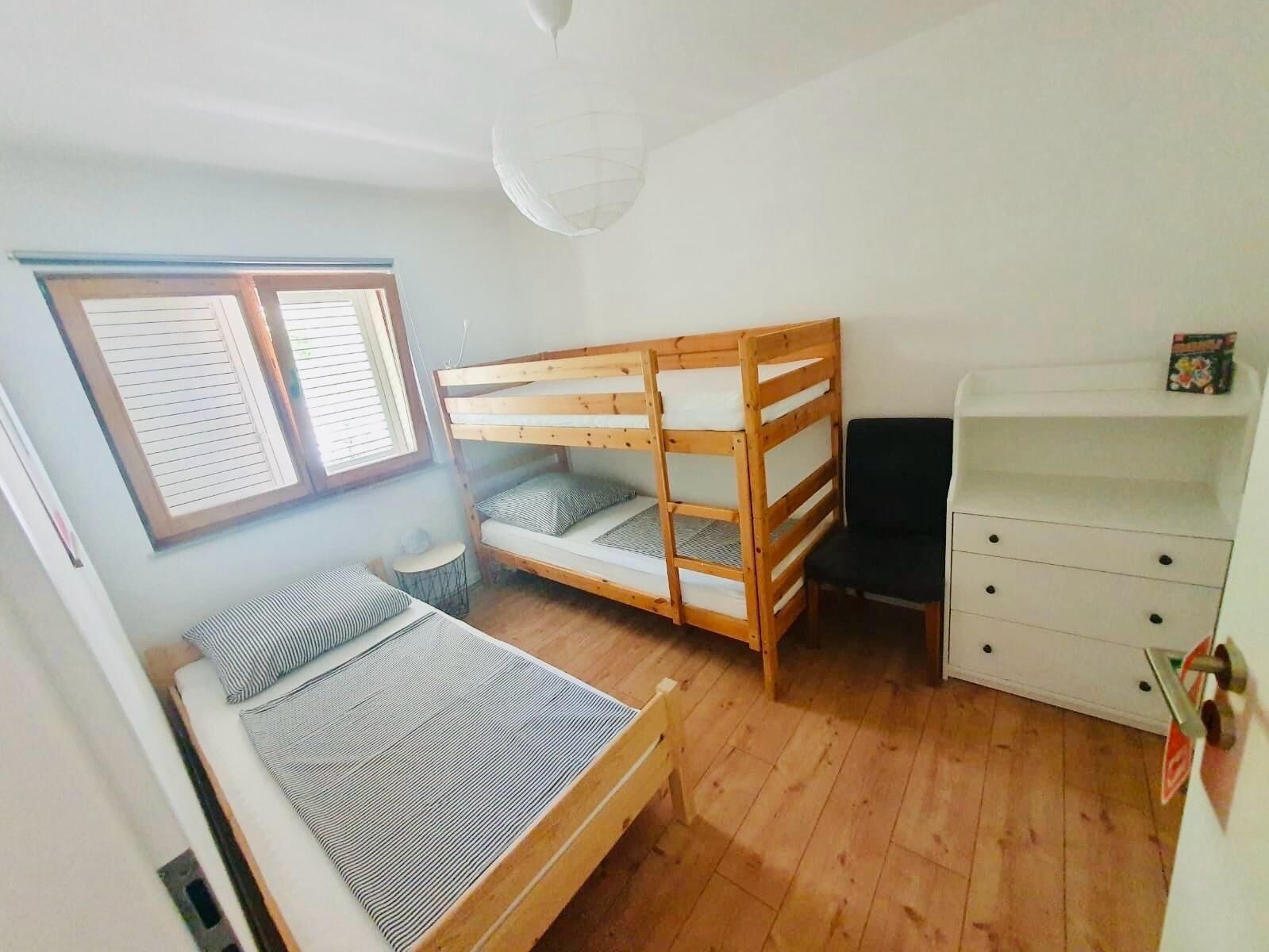 A small, tidy room with a bunk bed, a desk, and a chair.