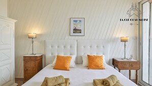 A hotel room with a large bed, two nightstands, a framed picture on the wall, and a window with a view.