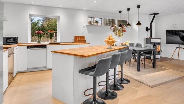 Une cuisine moderne dotée d’un îlot central, de tabourets de bar et d’un coin repas avec une table et des chaises.