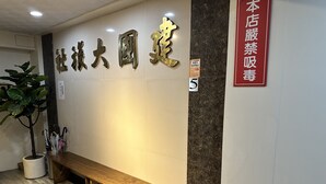 A reception area with a wooden bench, a potted plant, and a wall with large gold characters. - JianGuo (Luodong)