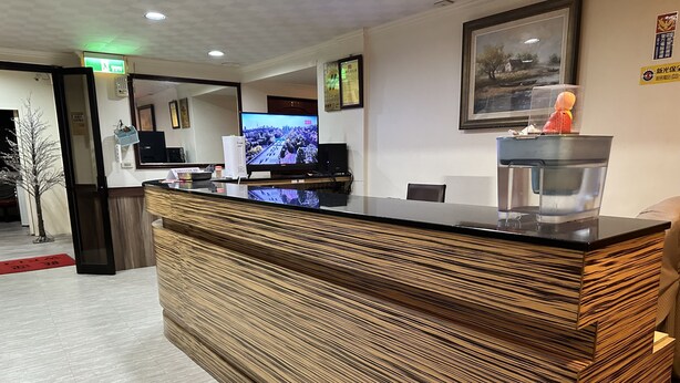 A reception desk with a wooden finish, a television screen, and a framed picture on the wall. - JianGuo (Luodong)