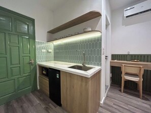 Uma cozinha compacta com porta verde, pia embutida e bancada de madeira.