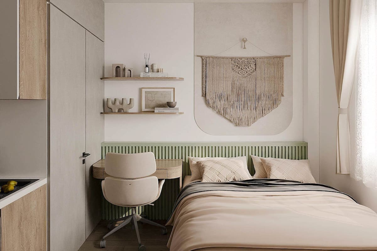 A modern bedroom with a bed, a desk, and a chair. There is a shelf with decorative items and a wall hanging.