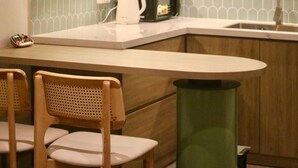Un área de cocina con mostrador de madera, dos sillas y un bote de basura.