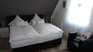 A bedroom with a large bed, a black chair, and a radiator. - Vacation apartment Wenge, 1-2 pers. (Ascheberg-Davensberg)