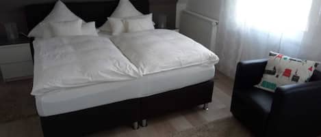 Un dormitorio con una cama grande, una silla negra y un radiador.