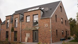 Ein zweistöckiges Backsteingebäude mit flachem Dach, Hausnummer 33, mit großen Fenstern und einem kleinen Balkon.