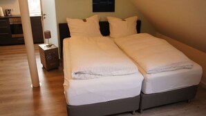 Ein Doppelbett mit weißer Bettwäsche in einem Zimmer mit Holzboden und einem dunklen Kopfteil.